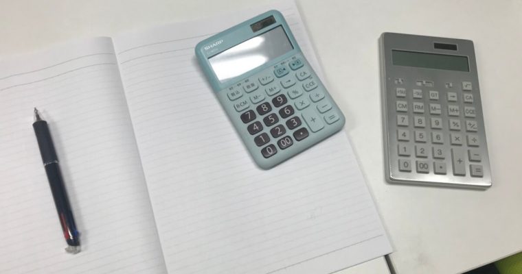机上に電卓とノートが広げられている様子
